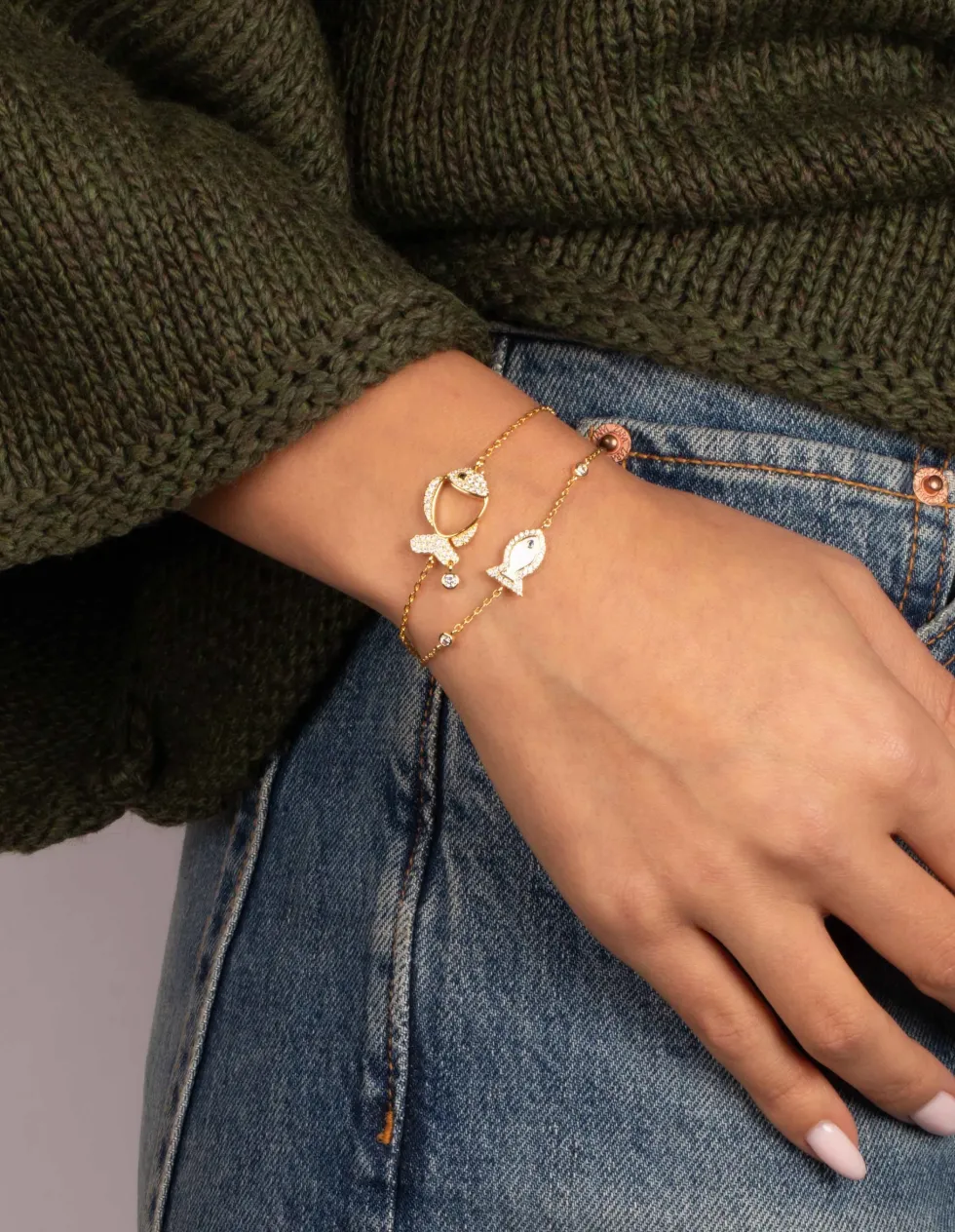 Two layered gold-tone chain bracelets with fish charms set with small stones