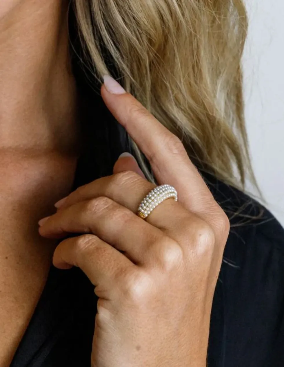 Wide ring covered in rows of small pearls, worn on a raised hand