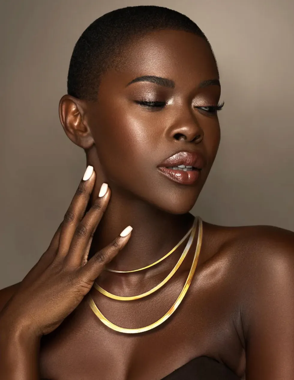 Model wearing three layered gold-tone flat chain necklaces