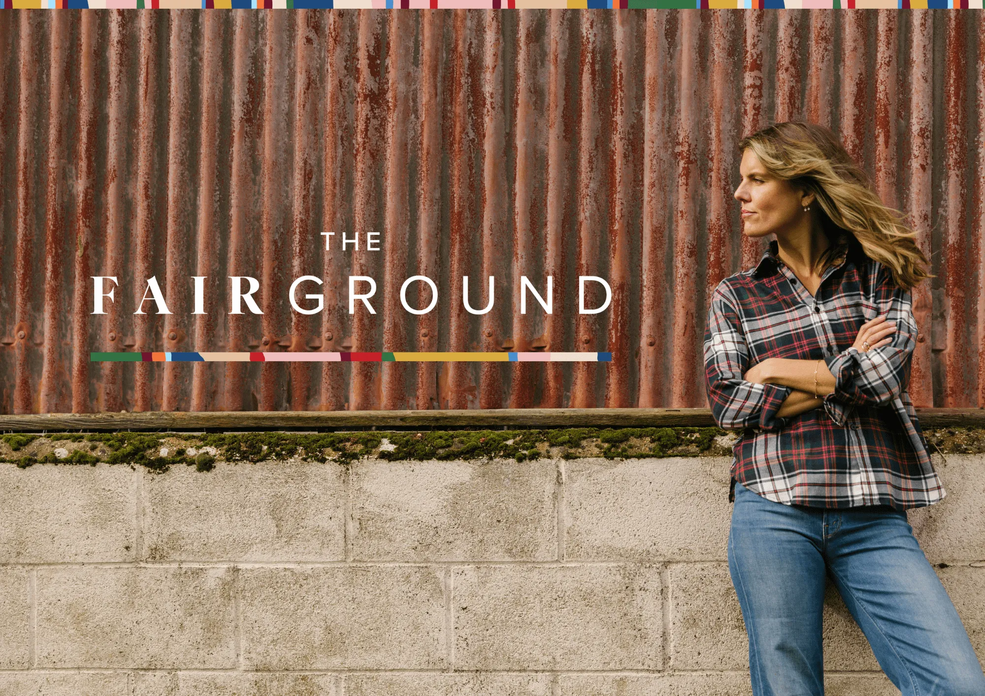 The FairGround logo on a rusted metal wall, beside a woman in a plaid shirt