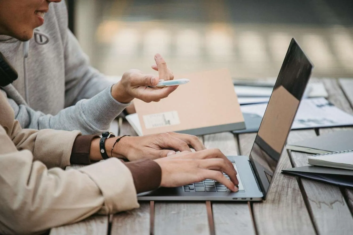 Two people at a laptop, one typing while the other points with a pen