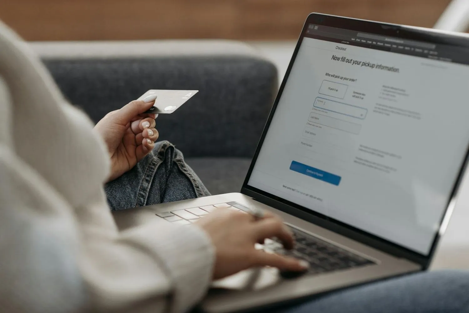 Person holding a payment card while filling out a checkout form on a laptop