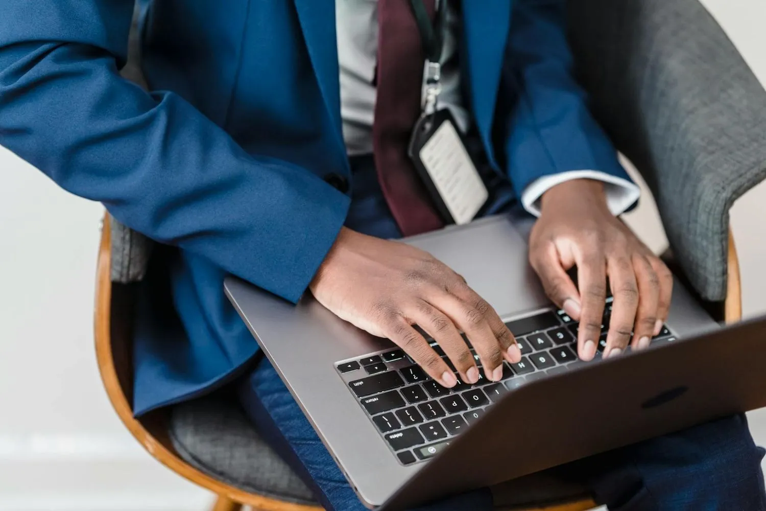 Person in a blue suit typing on a laptop on their lap